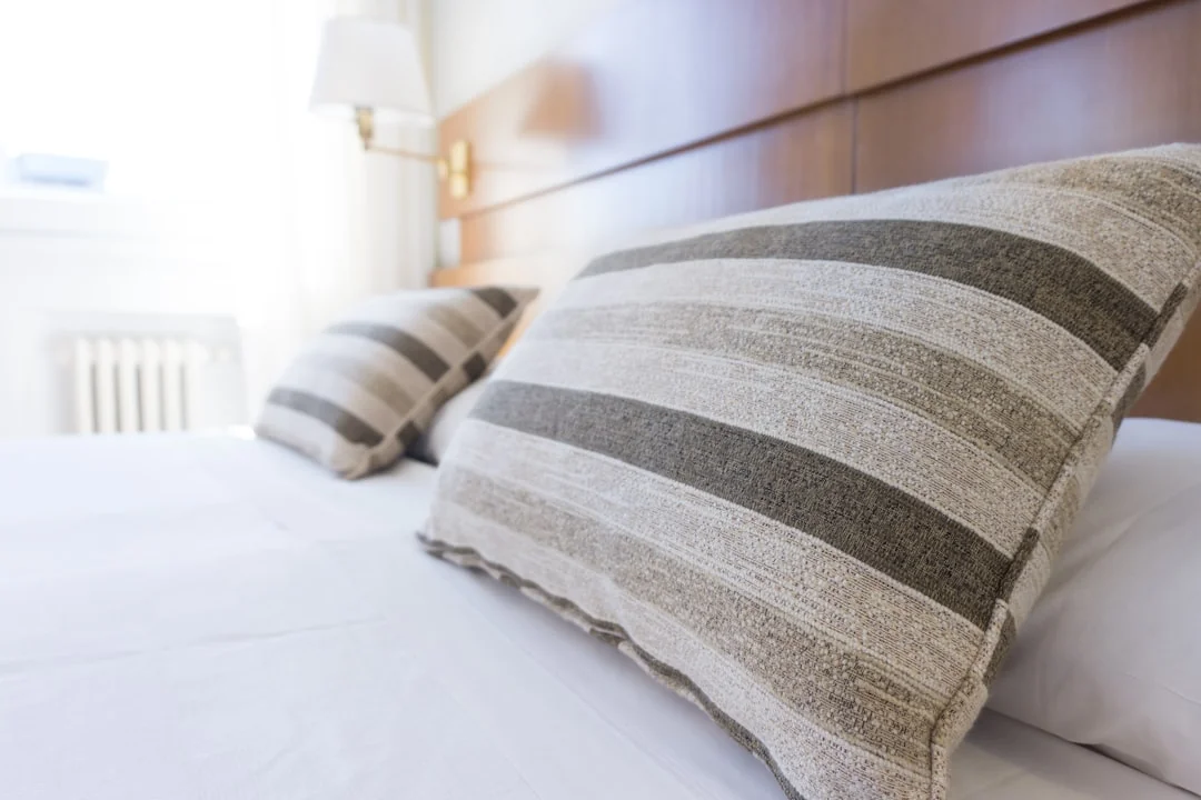 A hotel housekeeper neatly stacks fresh towels in a luxurious room setting.