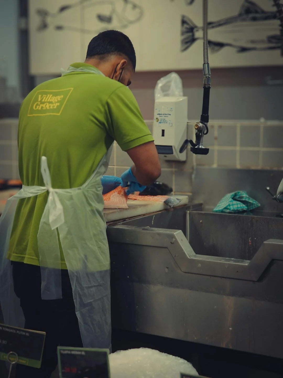 Vue de côté d’un jeune employé tenant une pile de serviettes blanches dans la salle de bain d’un hôtel de luxe