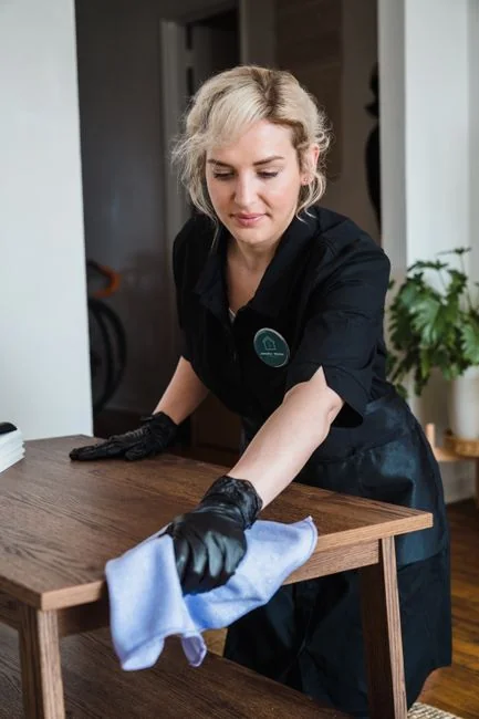 A housekeeper tidying the bed linens in a well-appointed hotel room.